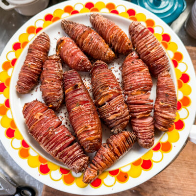 Crispy hasselback potatoes on a plate with a colorful rim.